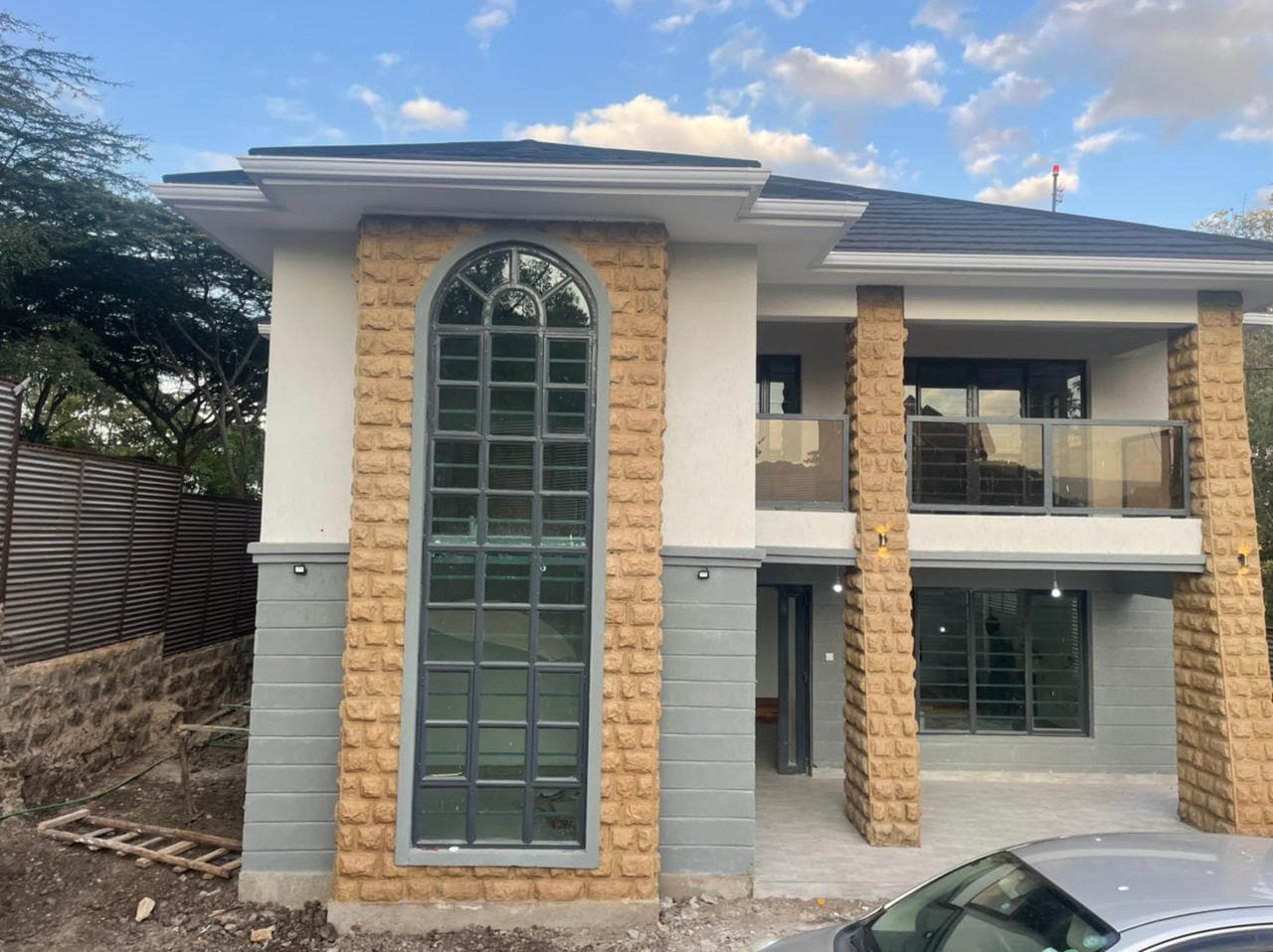 Completed Kaputei residence front elevation with a tall arched window and stone-faced vertical elements.